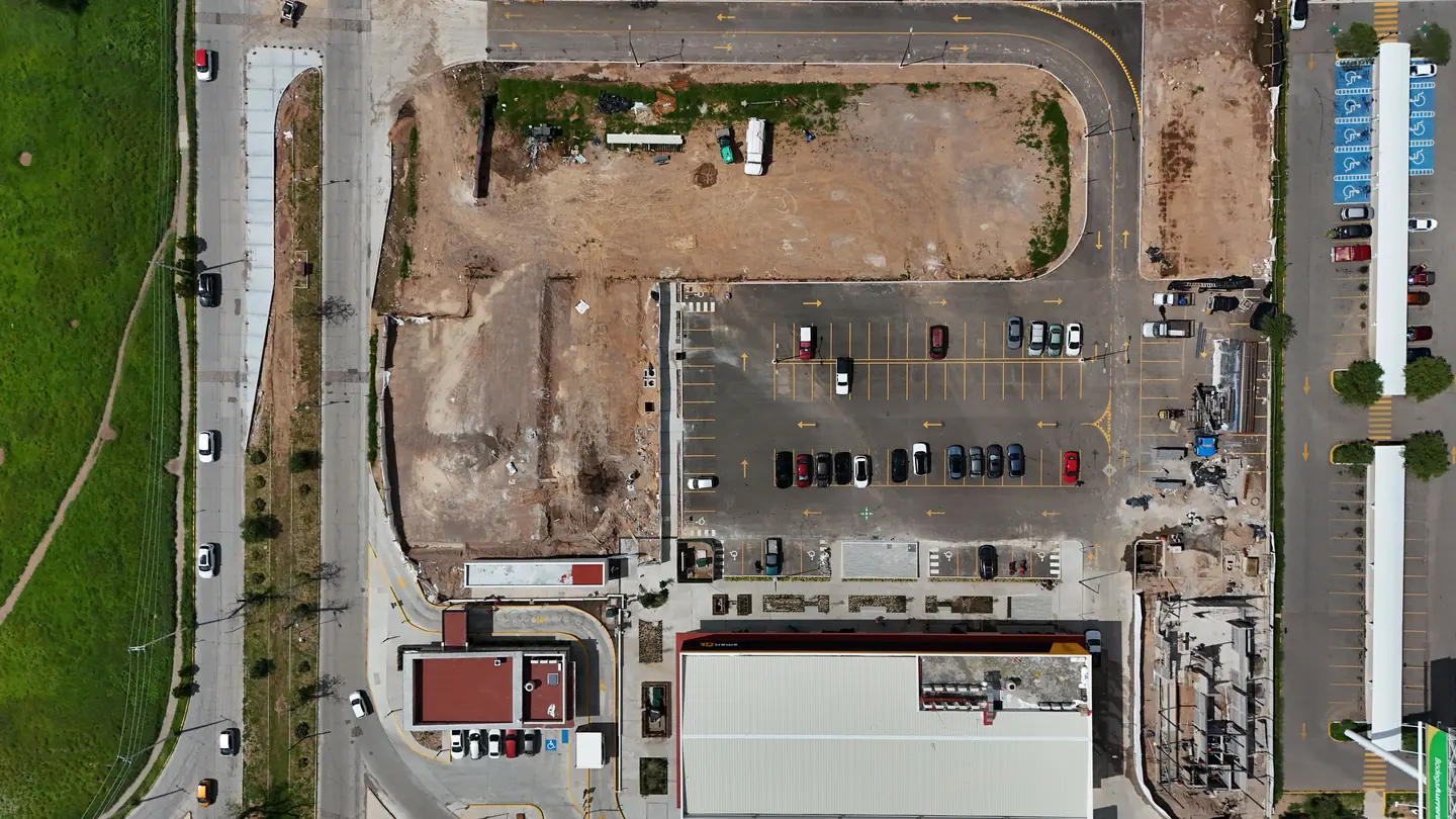 Vista cenital de una superficie en obras junto a un aparcamiento y viales