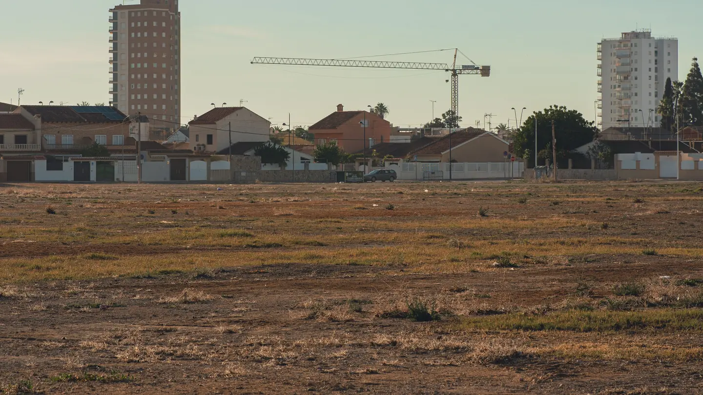 Terreno sin edificar junto a calles y edificios de una ciudad